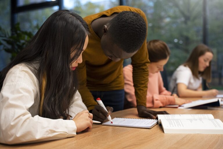 pessoas olhando para papeis sob a mesa. Representando alunos multirraciais estudando