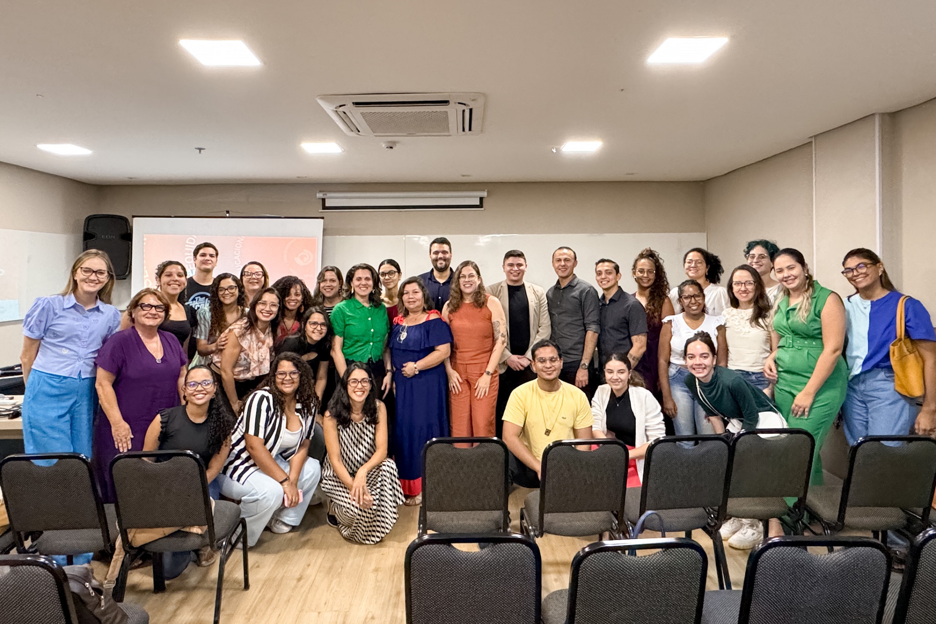 Imagem com todos os participantes e palestrantes do Seminário. Todas as pessoas estão olhando para frente, algumas agachadas, outras em pé, a maioria sorri para a foto.